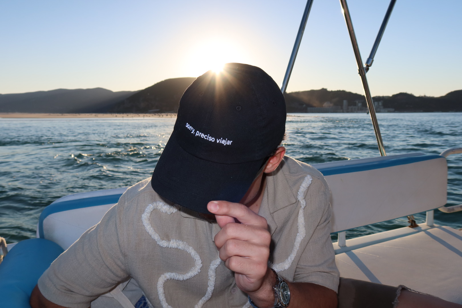 Boné Sorry, preciso viajar sendo usado durante uma viagem de barco ao entardecer, com o sol atrás